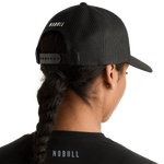 Woman Wearing Black Be U Trucker Hat Back Angle.